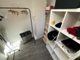 a small room with a shelf and clothes on it