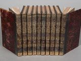 six old books are lined up in a row on a table