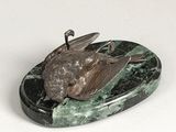 statue of a bird on a green marble base on a white surface