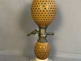 une lampe à huile à l'ancienne posée sur un socle blanc orné d'un motif jaune et noir