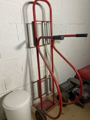 a red hand truck with a metal handle in a garage