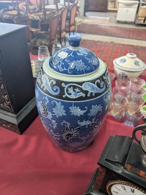 a blue and white vase sitting on a table next to a clock