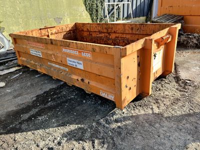 a dumpster sitting in the dirt outside of a building