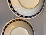 two plates with gold and blue designs on them on a table