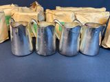 several silver pitchers and bags of coffee sit on a blue surface
