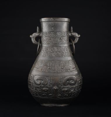 un vieux vase en métal orné de sculptures sur fond noir