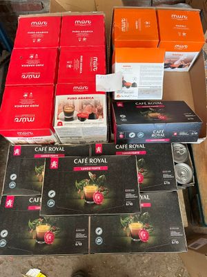 many boxes of coffee on the floor next to a person ' s feet