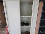 une armoire blanche avec une porte et des étagères dans une pièce