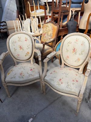 plusieurs chaises et une table dans une pièce avec beaucoup de meubles