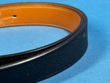 a black belt with a gold buckle on a blue surface
