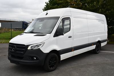 La camionnette blanche est garée sur le parking près des arbres.