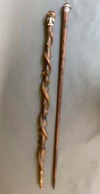 une paire de cannes anciennes en bois avec des poignées en métal, posées sur une surface blanche