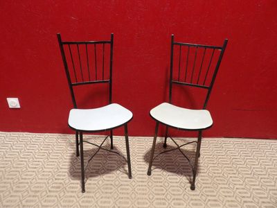 une paire de chaises pliantes noires et blanches adossées à un mur rouge