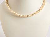 pearl necklace on a mannequin display with a white background