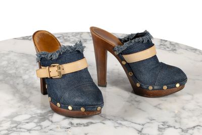 une paire de sabots en jean bleu à talon en bois posée sur une table en marbre