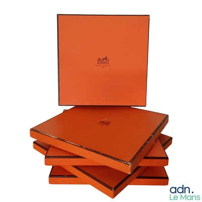 trois boîtes orange sont empilées les unes sur les autres sur une surface blanche