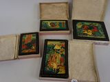 quatre petites boîtes en bois ornées de peintures, posées sur une table