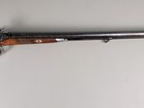 Un vieux fusil est accroché au mur d'une pièce.