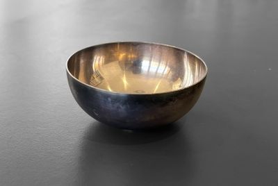 a metal bowl sitting on a table with a black surface
