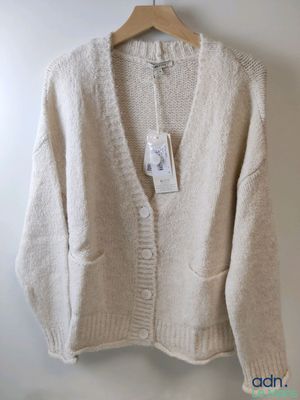 beige cardigan sweater hanging on a hanger on a white wall