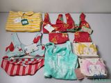 beaucoup de vêtements de bébé et un sac à main posés sur une table