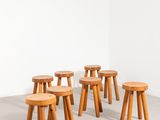 six wooden stools in a room with a white wall