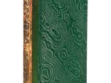 an old book with a green cover sitting on a white surface