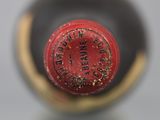 a close up of a red wine bottle with a gold cap