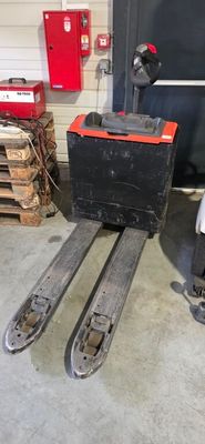 a fork lift truck parked in a garage next to a stack of pallets