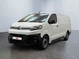 La camionnette blanche est garée dans une grande pièce au sol noir.