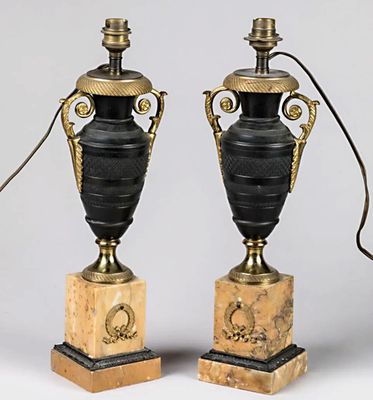 paire de lampes en forme d'urne, noires et dorées, sur des socles en marbre