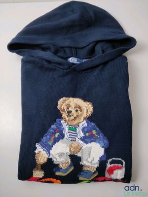 pull bleu orné d'un ours en peluche en tenue de marin et d'un seau rempli de jouets
