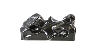 une sculpture noire représentant une paire de chaussures posée sur une surface blanche