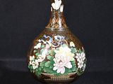 un vase sur lequel sont peintes des fleurs sur fond noir