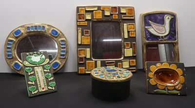 several pieces of art are displayed on a table with a mirror