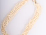 a necklace made of white glass beads with a gold clasp