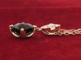 a close up of a black and gold necklace on a red surface