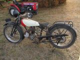 a motorcycle that is parked in the grass near a tractor