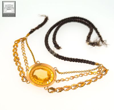 collier avec un pendentif doré et une chaîne ornée d'une pièce d'or sur fond blanc