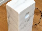 a white marble block on the floor next to a lamp