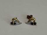 une paire de boucles d'oreilles en or et en argent posées sur une surface blanche