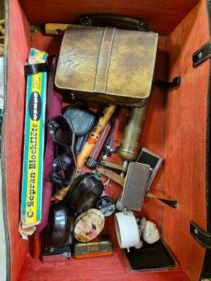 une valise pleine d'objets posée par terre