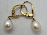 un gros plan sur une paire de boucles d'oreilles en perles posées sur une surface blanche