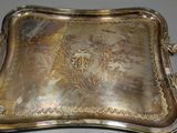 un plateau ancien en argent aux poignées ouvragées posé sur une table