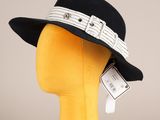 Le chapeau est noir et blanc, avec un ruban qui l'entoure.