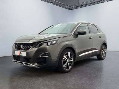 La voiture grise est garée dans une grande pièce aux murs blancs.