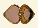 a gold compact case with a pink mirror inside of it