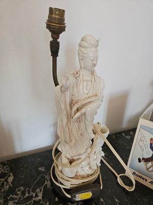 une statue représentant une femme tenant une bougie posée sur une table