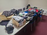 une longue table sur laquelle sont posés de nombreux vêtements
