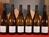 six bottles of wine are lined up on a red table